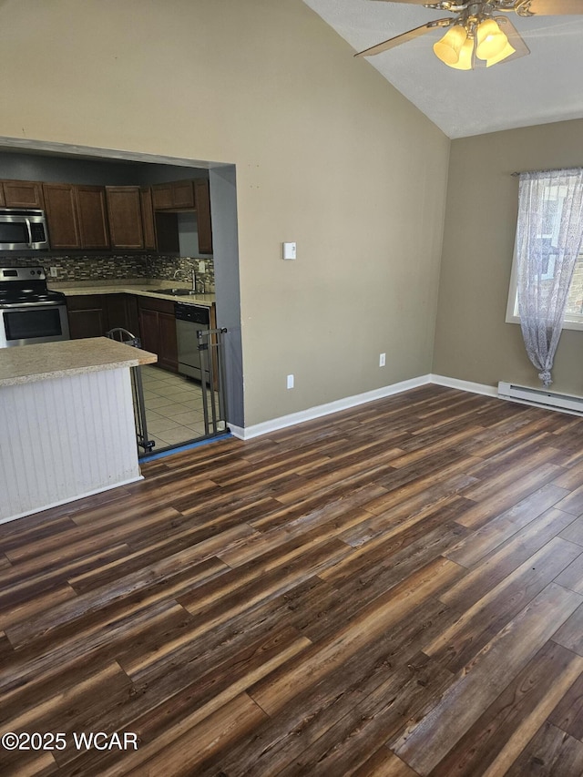 kitchen with stainless steel appliances, a sink, vaulted ceiling, backsplash, and dark wood finished floors