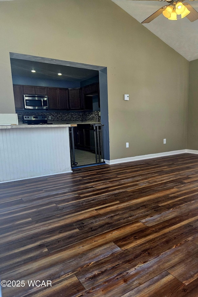 kitchen with dark wood-style floors, tasteful backsplash, vaulted ceiling, and stainless steel appliances