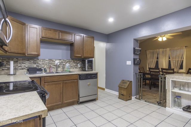 kitchen with stainless steel appliances, light countertops, decorative backsplash, a ceiling fan, and a sink