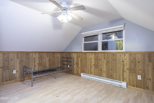 bonus room with lofted ceiling, wood walls, baseboard heating, and wood finished floors