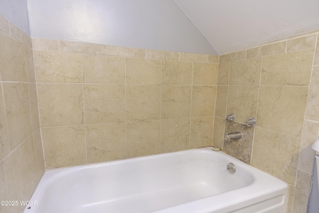 full bath featuring lofted ceiling and a tub