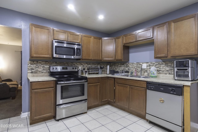 kitchen with light tile patterned floors, stainless steel appliances, a sink, and light countertops