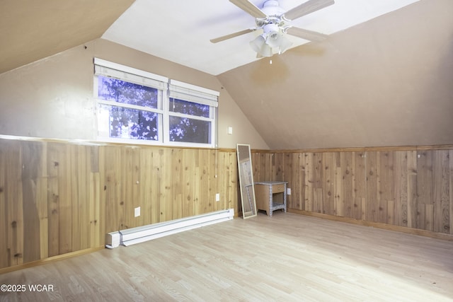 bonus room with vaulted ceiling, wooden walls, baseboard heating, and wood finished floors