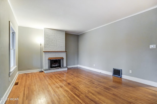 unfurnished living room featuring crown molding, hardwood / wood-style floors, and a brick fireplace