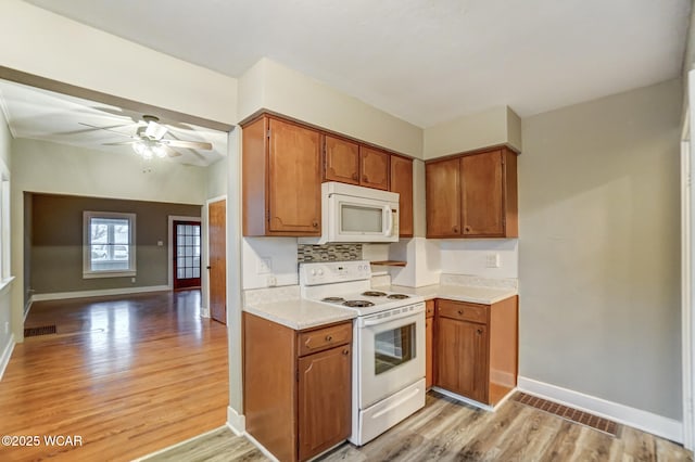 kitchen featuring ceiling fan, light wood-type flooring, white appliances, and decorative backsplash