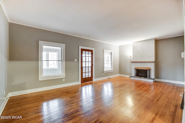 unfurnished living room with crown molding, wood-type flooring, and a brick fireplace