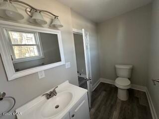 bathroom featuring toilet, baseboards, wood finished floors, and vanity