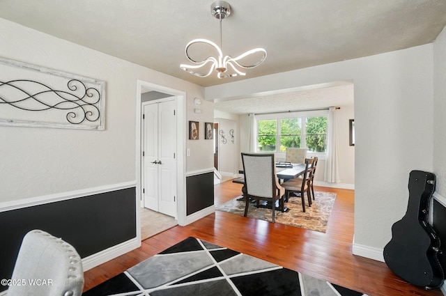 dining space featuring baseboards, a chandelier, and wood finished floors