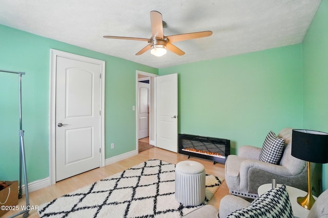 sitting room with baseboards, ceiling fan, and wood finished floors