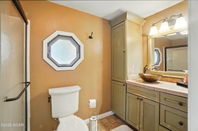 bathroom featuring vanity, toilet, baseboards, and an enclosed shower