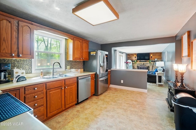 kitchen featuring brown cabinetry, stainless steel appliances, decorative backsplash, and a sink