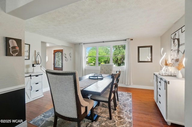 dining space with baseboards, a textured ceiling, and wood finished floors