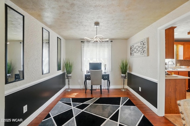 office area featuring a sink, a chandelier, a textured wall, and wood finished floors