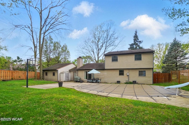rear view of property with a yard, a patio area, an outdoor structure, and fence