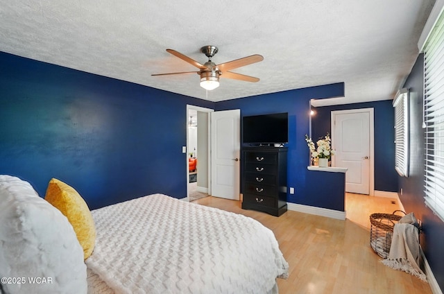 bedroom with multiple windows, a textured ceiling, wood finished floors, and baseboards