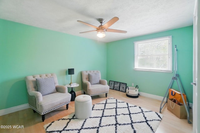 sitting room with a textured ceiling, baseboards, wood finished floors, and a ceiling fan