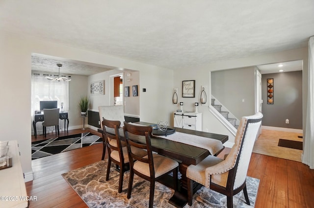 dining room with baseboards, stairs, a notable chandelier, and hardwood / wood-style flooring