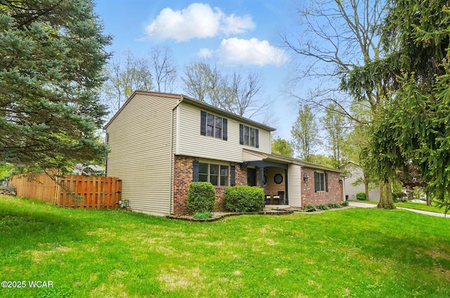traditional home featuring fence, brick siding, and a front yard