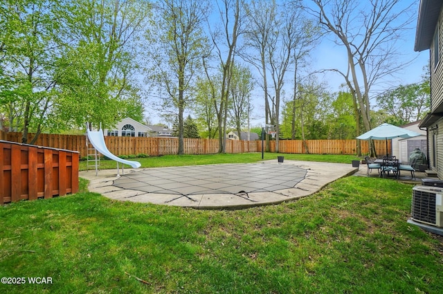 view of yard with a fenced backyard, a patio area, and central AC unit