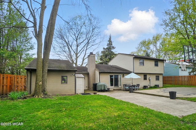 back of house with a yard, a chimney, fence, and a patio area