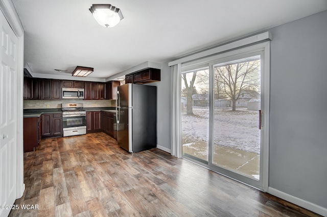 kitchen with dark brown cabinetry, hardwood / wood-style flooring, stainless steel appliances, and decorative backsplash