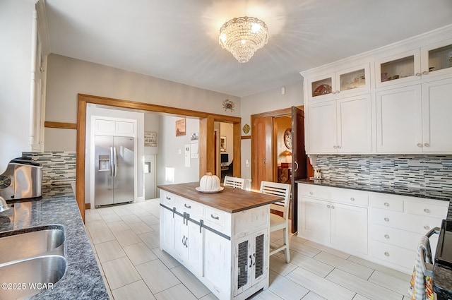 kitchen with tasteful backsplash, white cabinetry, stainless steel built in fridge, and sink