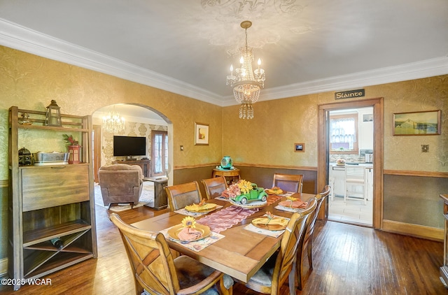 dining space with a notable chandelier, crown molding, and wood-type flooring