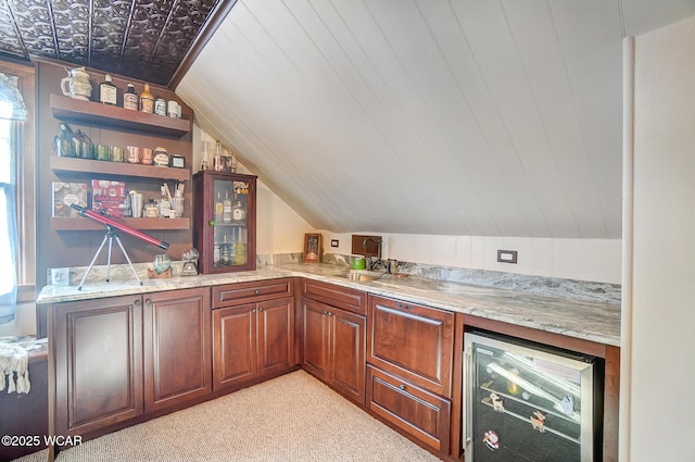 bar with wine cooler, vaulted ceiling, light stone countertops, and light carpet