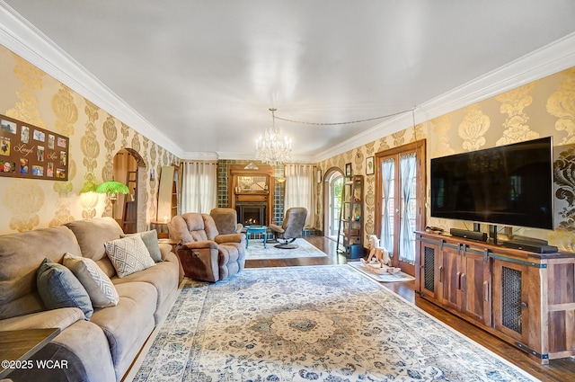 living room featuring wood-type flooring, ornamental molding, and a notable chandelier