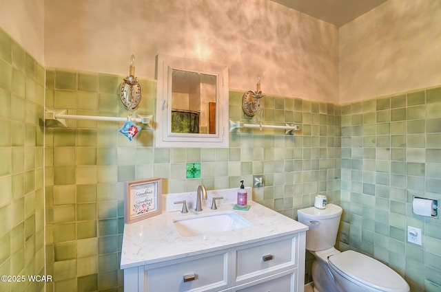 bathroom featuring vanity, tile walls, and toilet