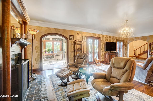 living room featuring hardwood / wood-style flooring, ornamental molding, a fireplace, and an inviting chandelier