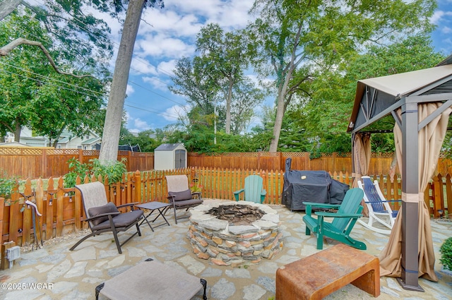 view of patio / terrace featuring a grill, a gazebo, a storage unit, and an outdoor fire pit