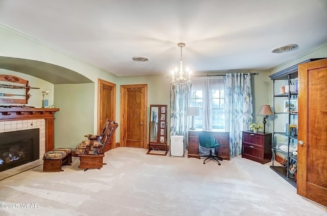 living area featuring an inviting chandelier, ornamental molding, a tiled fireplace, and light carpet