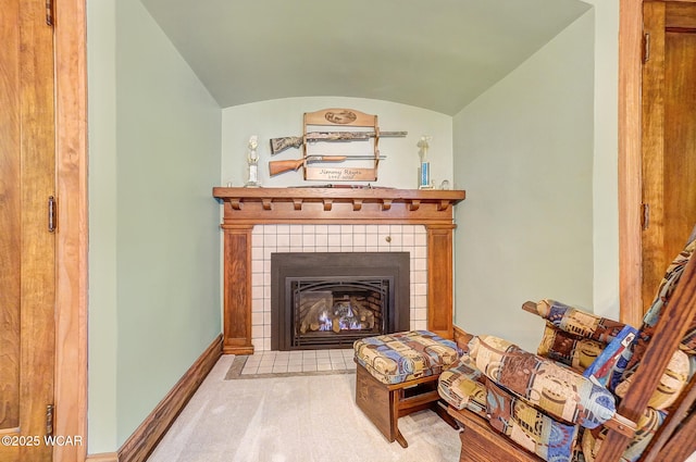 living area with a tiled fireplace and vaulted ceiling