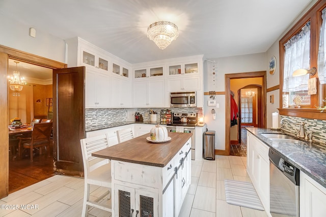 kitchen with sink, appliances with stainless steel finishes, an inviting chandelier, a center island, and white cabinets