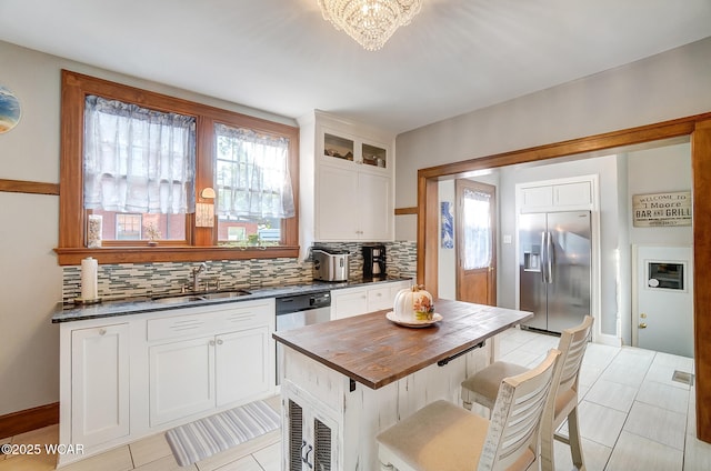 kitchen with sink, tasteful backsplash, stainless steel fridge, a wealth of natural light, and white cabinets