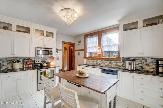 kitchen with sink, white cabinetry, an inviting chandelier, stainless steel appliances, and decorative backsplash