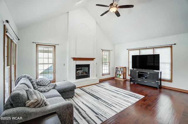 living room featuring a fireplace, dark wood-type flooring, high vaulted ceiling, and a healthy amount of sunlight