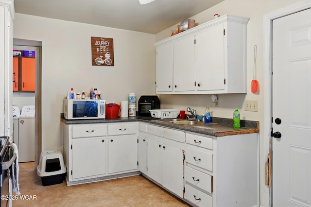 605 Hendricks Ave, Saint Marys, OH 45885 - kitchen with independent washer and dryer, white microwave, dark countertops, a sink, and white cabinets