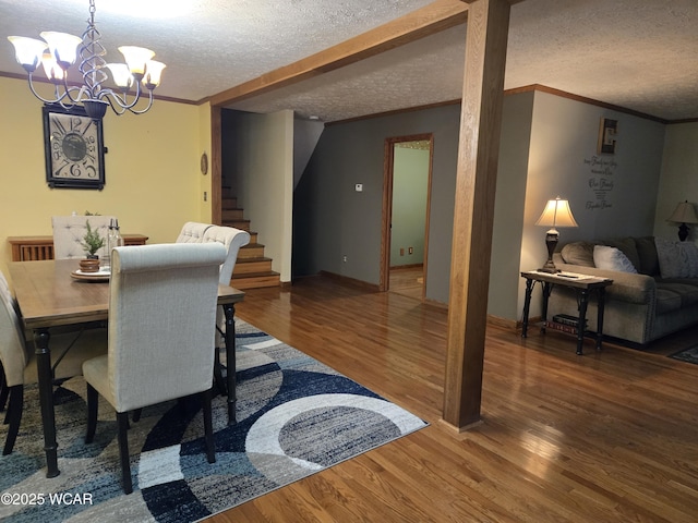 dining room with crown molding, an inviting chandelier, hardwood / wood-style floors, and a textured ceiling