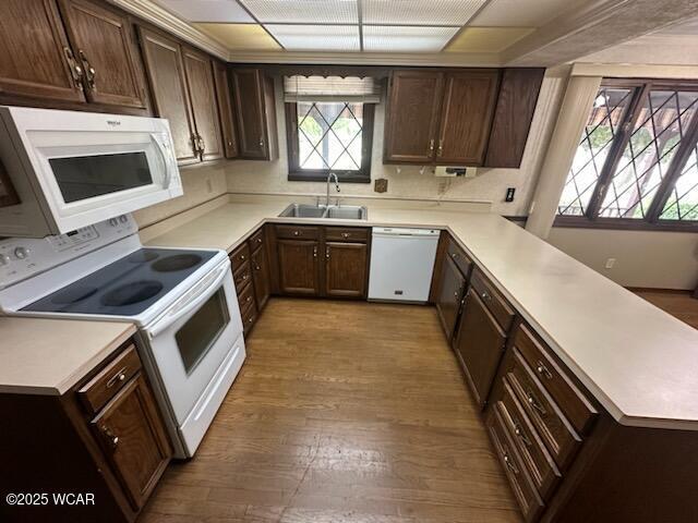 1317 Timberlane Dr, Lima, OH 45805 - kitchen featuring white appliances, a peninsula, wood finished floors, light countertops, and dark brown cabinets