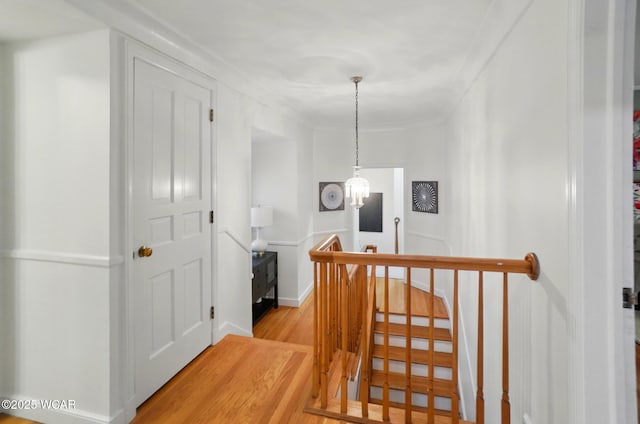 hall featuring a chandelier, an upstairs landing, and light wood-style flooring