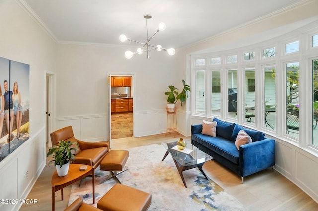living room with crown molding, a decorative wall, light wood finished floors, and a notable chandelier