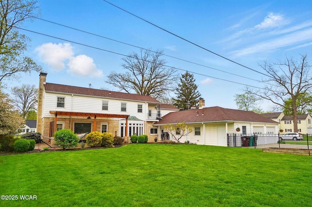 rear view of house featuring driveway, a chimney, fence, a yard, and an attached garage