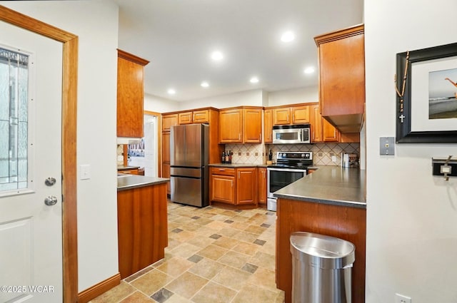 kitchen with decorative backsplash, appliances with stainless steel finishes, dark countertops, brown cabinets, and recessed lighting
