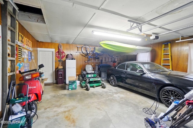 garage featuring a garage door opener, freestanding refrigerator, and wood walls