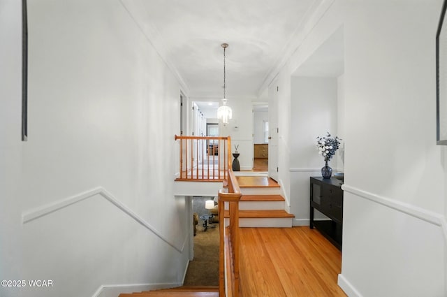 staircase featuring baseboards, ornamental molding, and wood finished floors