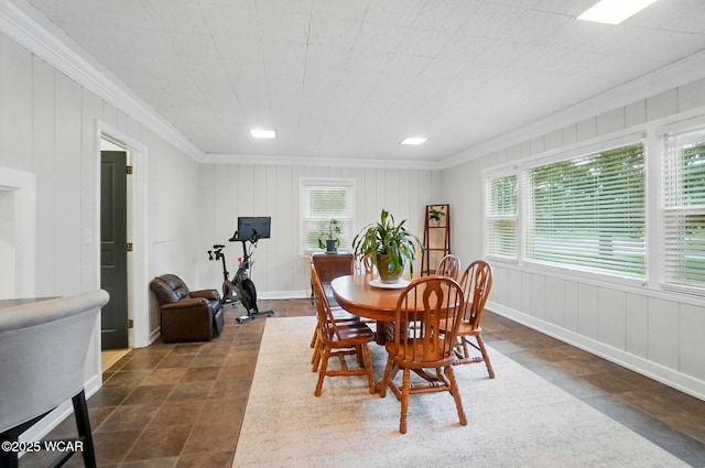dining room with baseboards, ornamental molding, dark tile patterned floors, and a decorative wall