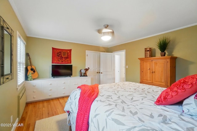 bedroom with crown molding, light wood-style flooring, and a closet