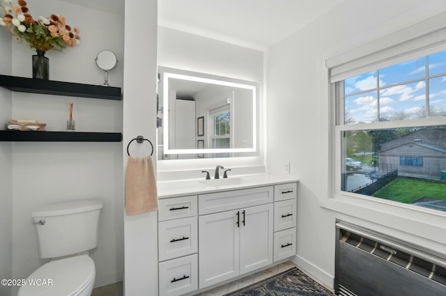 half bathroom featuring vanity, marble finish floor, radiator, toilet, and baseboards